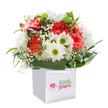 Brimming with energy and local charm, this bouquet encapsulates a sense of pure joy-much like a walk through Camberwell's verdant parks on a bright morning. Arranged inside a spotless, contemporary white gift bag, the display overflows with coral and red carnations whose everso-ruffled petals invite the senses. These are thoughtfully paired with pure white daisies, their cheerful yellow-green eyes radiating optimism and warmth. Airy clouds of baby's breath add softness throughout, supporting the main blooms with an almost ethereal grace. Encircling the arrangement, broad, glossy green leaves cradle every flower, while unopened buds, tinged with royal purple, offer a promise of continued beauty-echoing the creative renewal found in Camberwell's galleries. Each stem is meticulously placed, achieving a perfectly rounded fullness that suggests abundance and thoughtful preparation. The sturdy white ribbon handles atop the gift bag offer both function and understated style, making it easy to carry along for a birthday celebration, mark a milestone, or share a moment of happiness with friends or family in SE5. Overall, this presentation is a modern expression of Camberwell's vibrant spirit, blending freshness, artistry, and heartfelt intention in one striking arrangement.